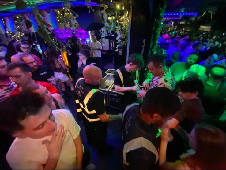 A C&D door supervisor checking ID and wristbands at a busy Manchester venue